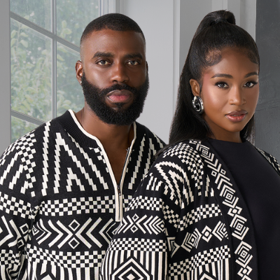 Two people wearing black and white patterned outfits standing close together.