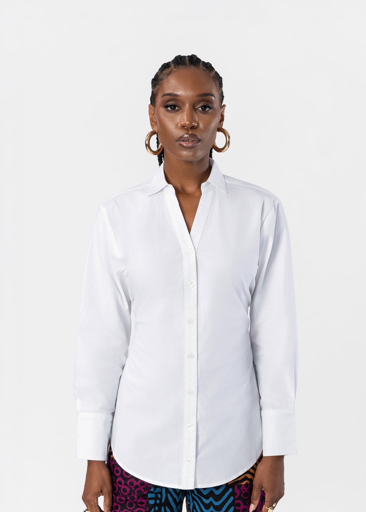 A woman modeling a white long-sleeve button-up shirt against a plain light gray studio background.