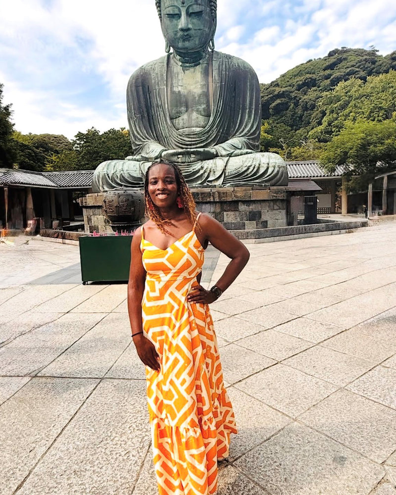 Woman posing in a gold and cream tribal-print maxi dress at an outdoor temple