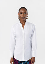 A woman modeling a white long-sleeve button-up shirt against a plain light gray studio background.